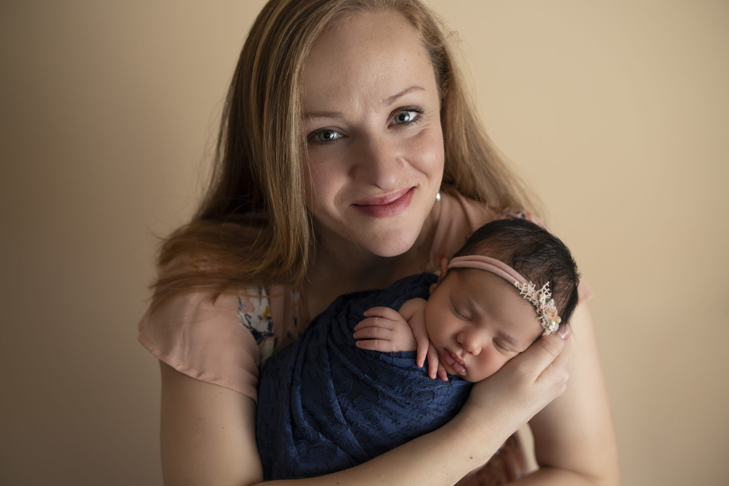 A mother holding her newborn baby is pictured here. Image take by Cedar Rapids newborn photographer, Ali Kerr.