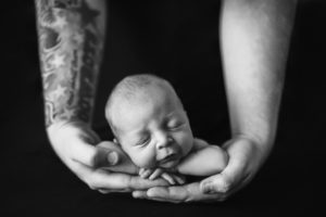 This image shows a father holding his daughter after she has fallen asleep in his arms. Image take by Cedar Rapids newborn photographer, Ali Kerr.