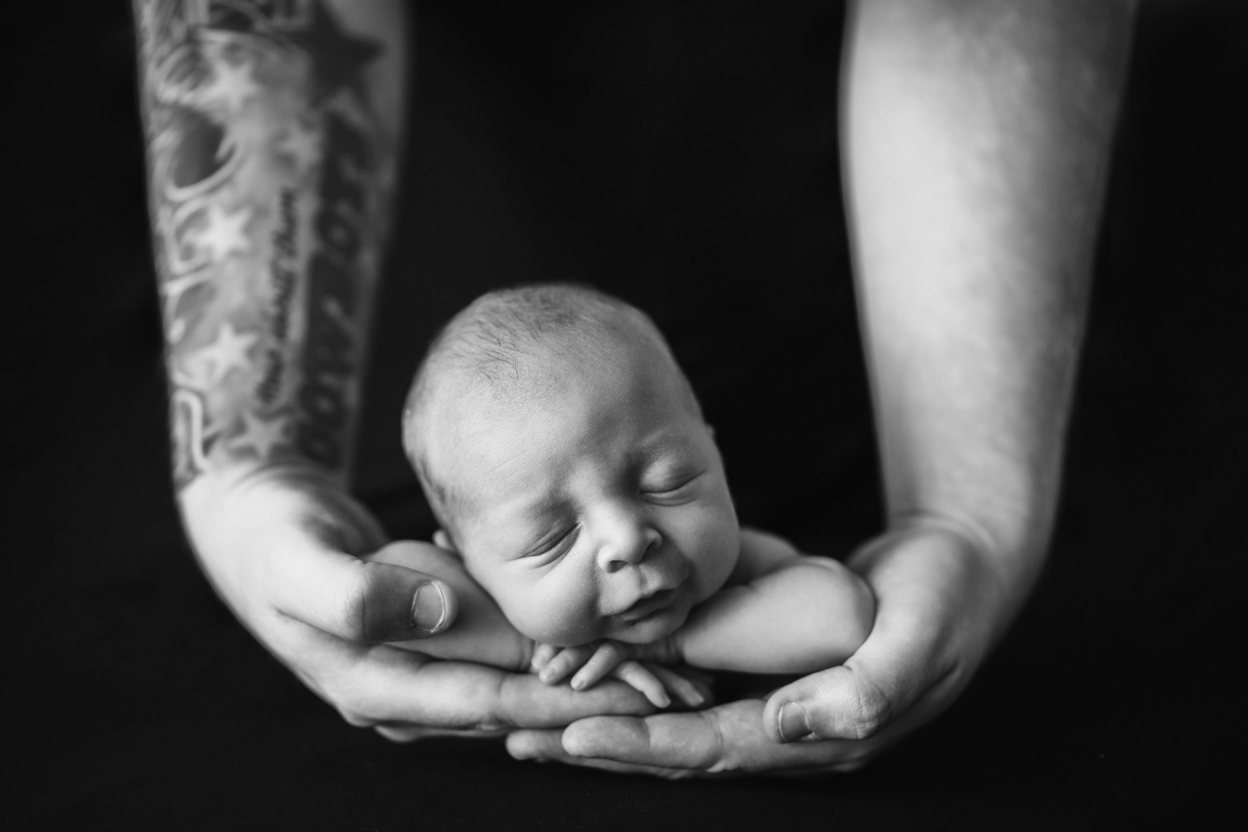 Iowa City newborn baby sleeping in father's hands